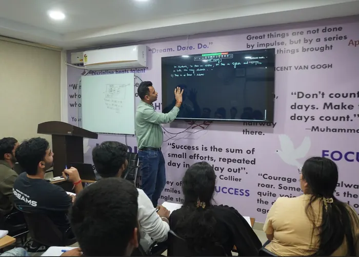 Teacher writing on a classroom board while seated students watch