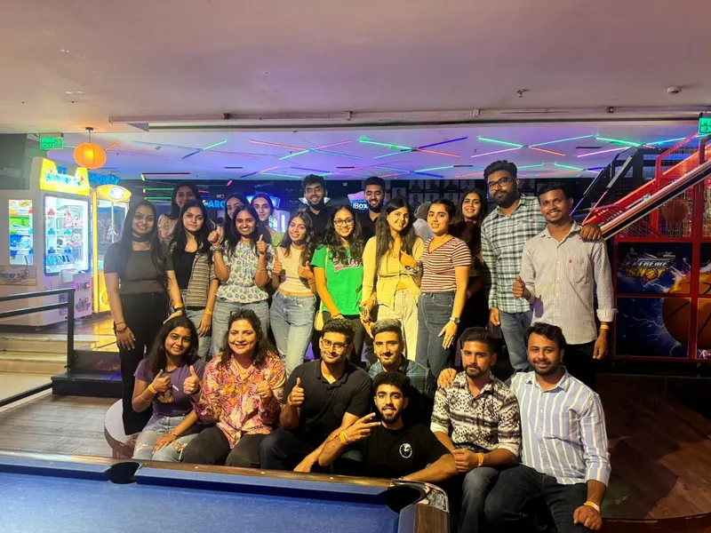 A seated and standing group posing by a pool table
