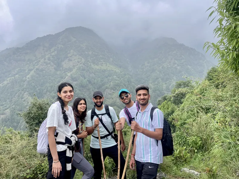 Five trekkers smiling in front of a misty mountain valley