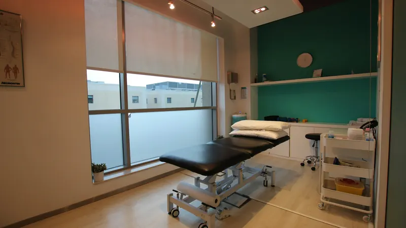 Treatment room with padded examination table and shelves beside windows