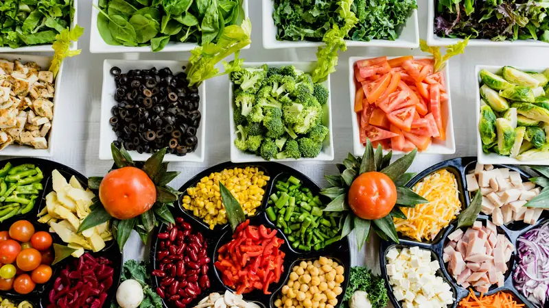 Colourful chopped vegetables arranged in separate bowls and white trays