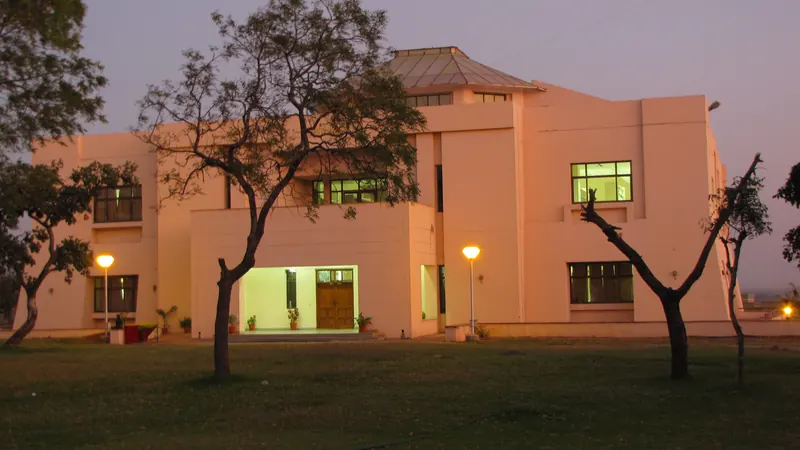 IIM Indore library building beyond trees and lawn at dusk