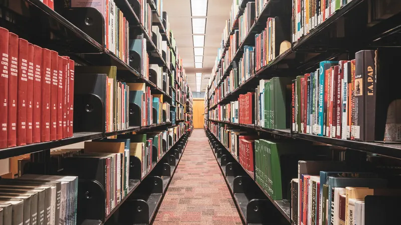 Long library aisle between bookcases with reddish floor tiles below