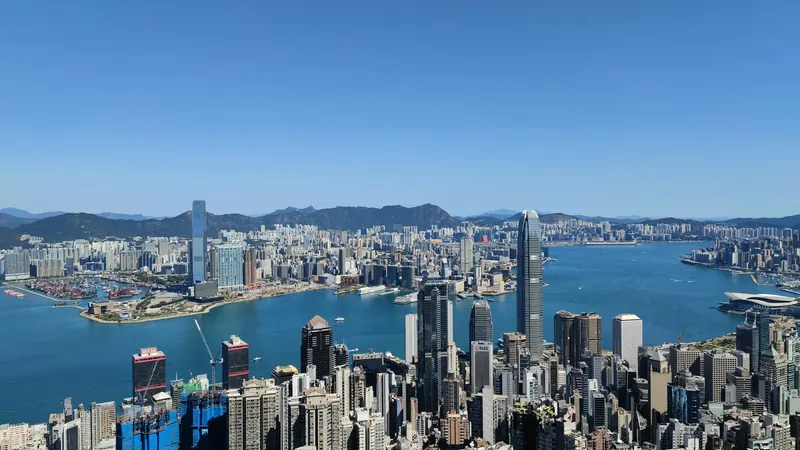 Hong Kong buildings overlooking Victoria Harbour beneath a clear blue sky