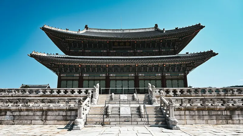 Palace hall above stone steps beneath a clear Seoul sky