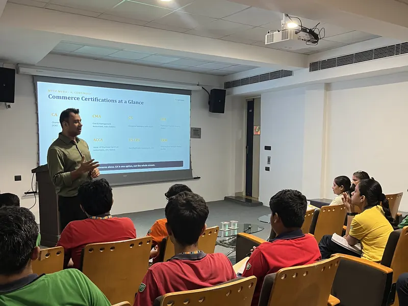 Seated students facing Anshul Wadhwa beside a slide on commerce certifications