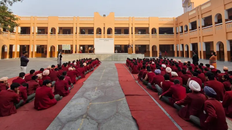 Students seated in a school courtyard with Anshul Wadhwa speaking at the side