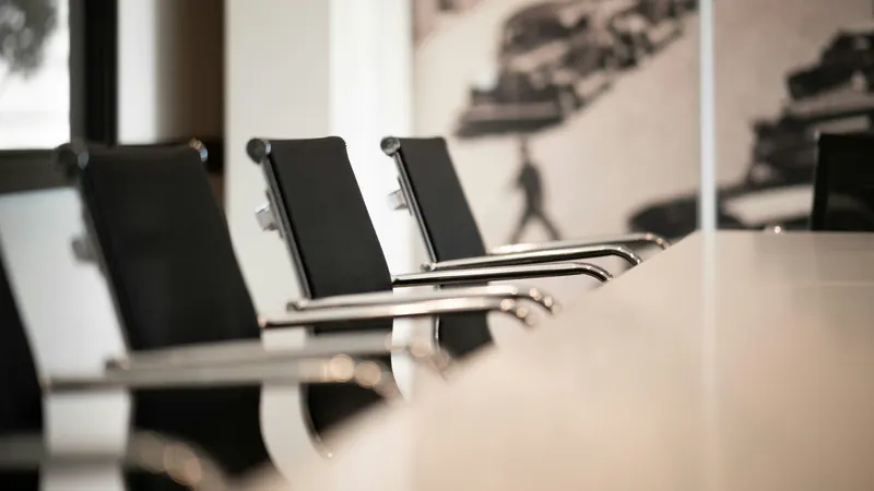 Black office chairs lined up beside a long conference table