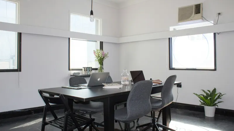 Laptop and chairs around a meeting table in a bright room