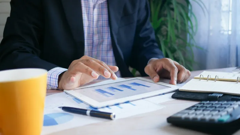 Hands reviewing charts on a tablet beside papers and calculator