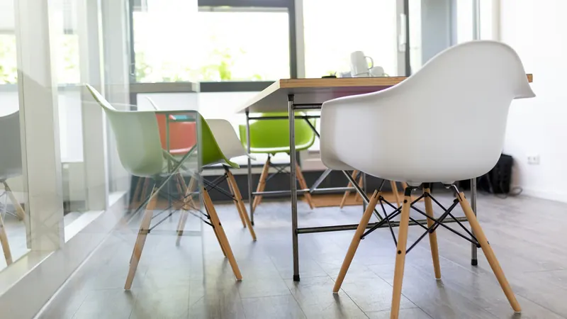 White chairs and a table beside windows in a bright room