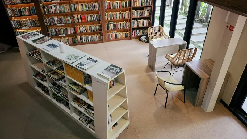 Library shelves and display tables beside broad floor to ceiling windows
