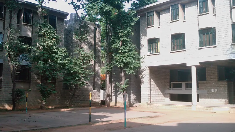 Stone campus buildings at IIM Bangalore beside trees and courtyard
