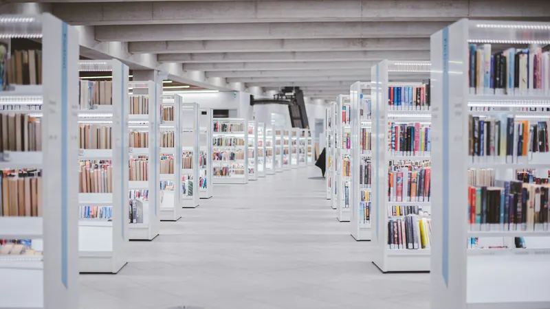 Bright library aisle between white shelves filled with books