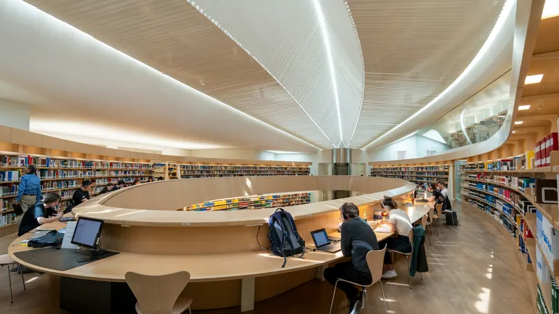 Curved library study counter beneath a sculpted white ceiling
