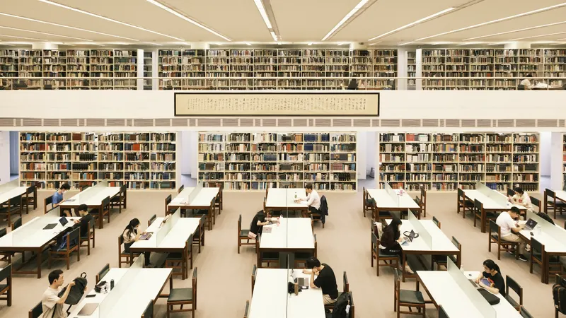 Readers seated at tables beneath several levels of library bookshelves