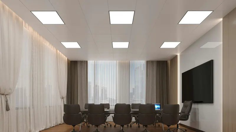 Dark chairs around a conference table beneath rectangular ceiling lights