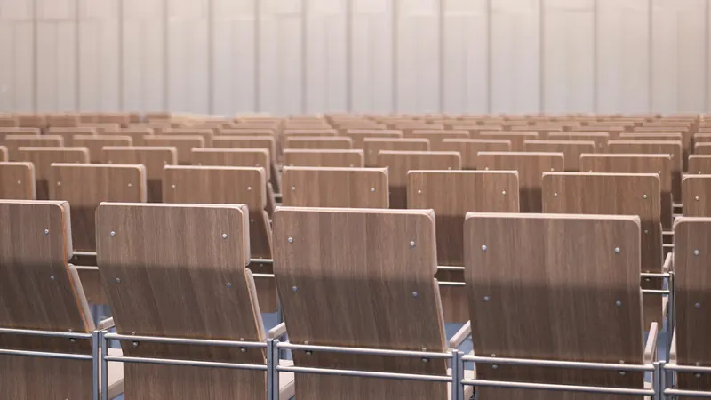 Rows of wooden auditorium seats facing the front of a hall