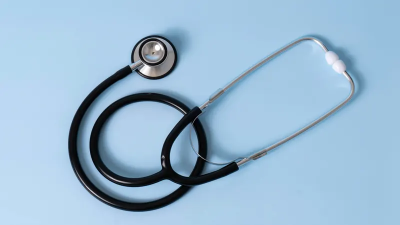 Black stethoscope with silver earpieces resting on a light blue background
