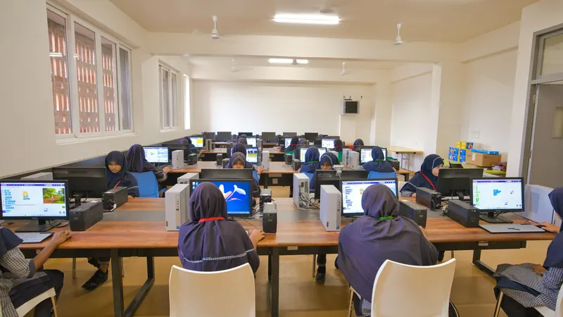 Students viewed from behind at computers in a bright classroom