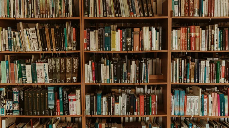Rows of books arranged across tall wooden shelves in library