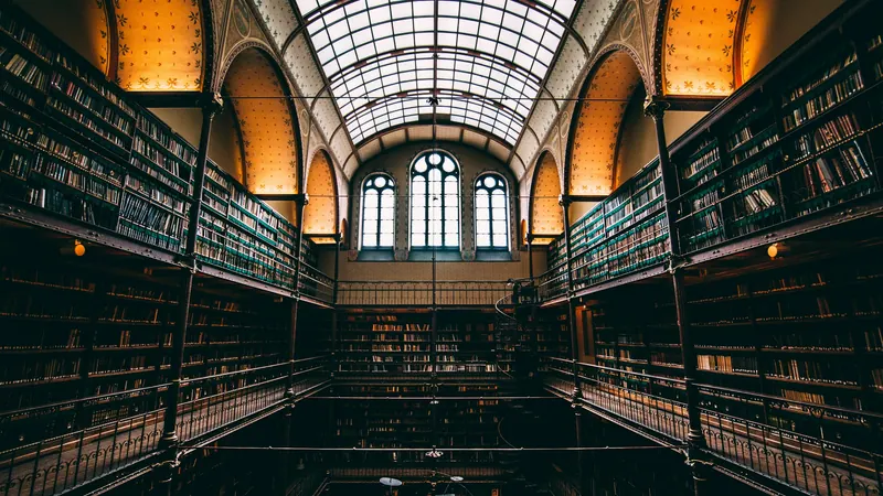 Tall library bookshelves beneath an arched glass ceiling and windows