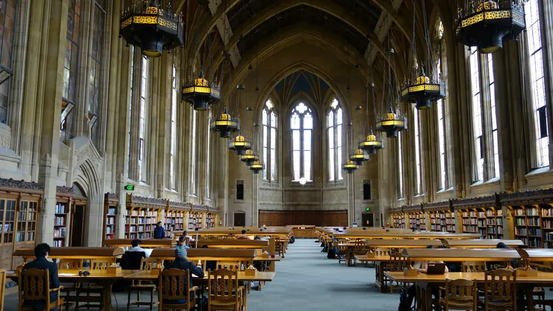 Library reading desks beneath stone arches and tall pointed windows