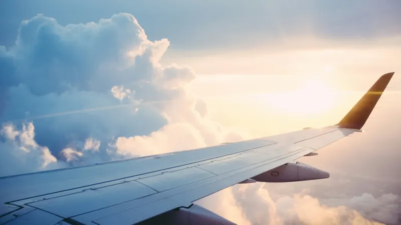 Airplane wing extending above clouds lit by a warm sunset