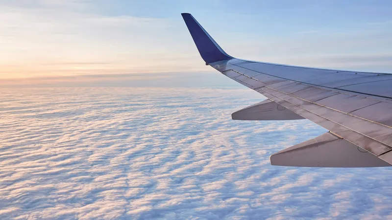 Airplane wing above a broad layer of clouds at sunset