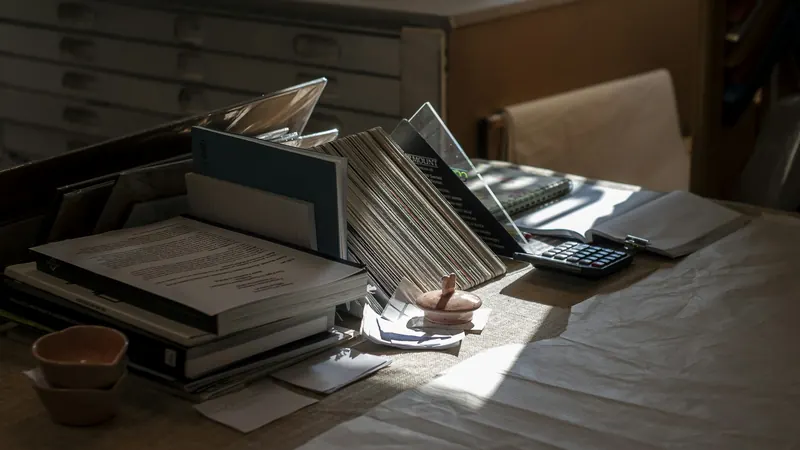 Hand writing beside open books and laptop on a sunlit table