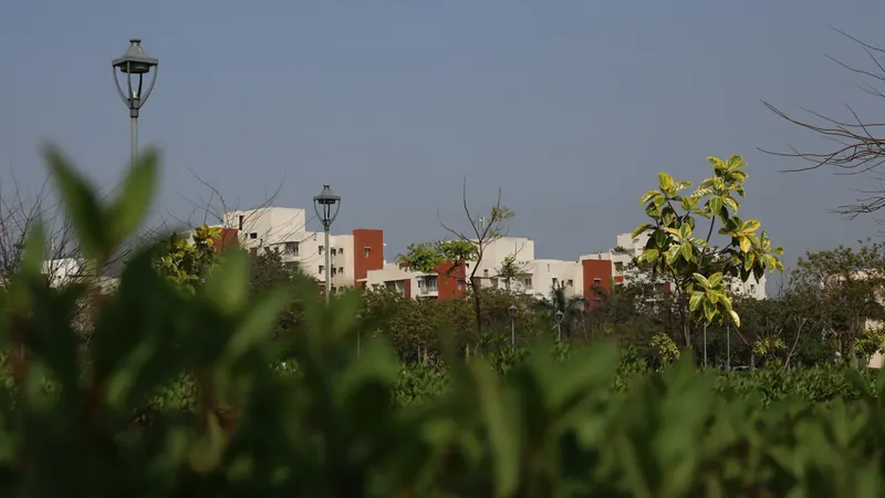 Campus buildings seen beyond greenery and a tall outdoor lamp